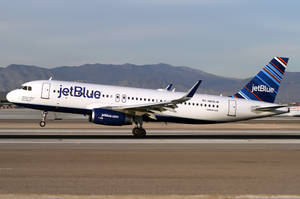 JetBlue飛機喺跑道上，背景有山