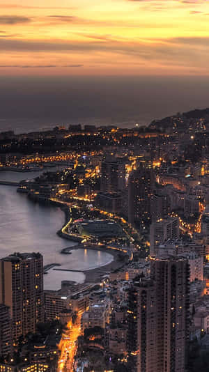 日落時分燈火通明的摩納哥沿海城市，金色天空和海景。
