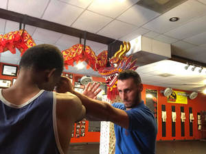 武術教練在有紅色龍裝飾的練習室中教導學生詠春拳。