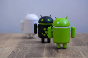 木質表面上的三個綠色、黑色和白色Android機械人公仔。