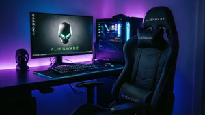 Alienware 遊戲設置，帶有發光的藍色和紫色燈光在書桌椅子、顯示器和PC上