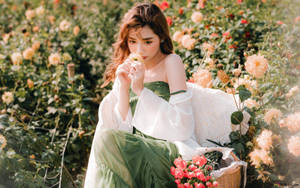 身穿綠色連衣裙的女子在花園裡聞花香，旁邊放著一籃鮮花。