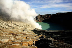 火山口噴出蒸氣，帶有藍綠色水和岩石地形。 — 湖景 壁紙