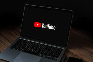 筆記型電腦在木桌上顯示YouTube標誌於黑色螢幕 — AMOLED 壁紙