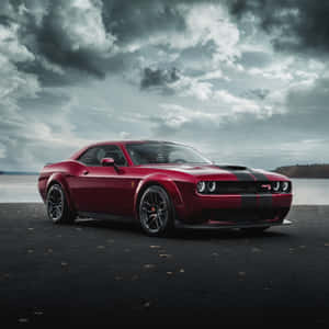 紅色Dodge Challenger SRT在暴風天空下停泊在近水處。