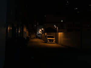 夜間白色貨車停泊在黑暗小巷中，被路燈照亮。