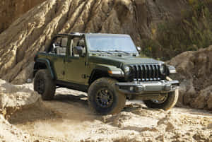 橄欖綠色Jeep Wrangler在岩石地形附近攀爬沙坡