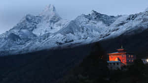 紅色修道院在黃昏時分，映襯著雪山和黑暗森林，閃閃發光。