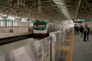 乘客在火車月台上等候，一列綠色和白色的火車正在接近。