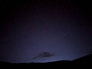 繁星點點的夜空，有流星劃過黑暗的山丘和雲。