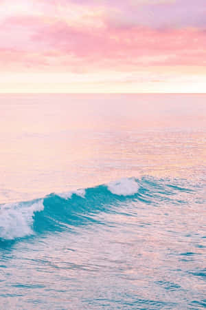 碧綠海面上的粉紅日落與捲曲的海浪