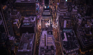 夜晚密集城市景觀的鳥瞰圖，有發光的燈光和高的建築物。 — 午夜 壁紙