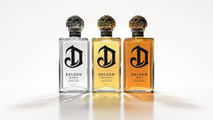 三瓶Deleón龍舌蘭酒在白色表面上排列展示。
