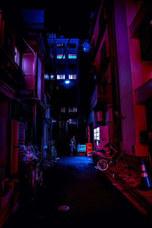 夜晚霓虹燈照亮的小巷，停有電單車和單車。