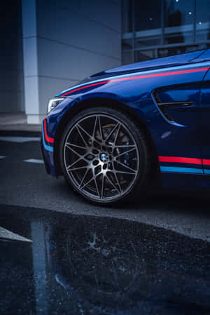 帶有賽車條紋的藍色BMW M4夜間停在濕漉漉的路面上。