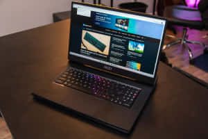 黑色 MSI 遊戲筆記型電腦配備 RGB 鍵盤，放在木桌上顯示科技網站。