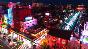 擁擠的日本城市街道夜景鳥瞰圖，霓虹燈和傳統建築風格。 — 2560x1440 壁紙