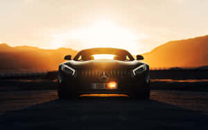 黑色 Mercedes-AMG GT 跑車在日落時分，背後有山脈。