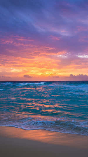 夕陽映照海洋，天空色彩繽紛，沙灘上輕柔的海浪