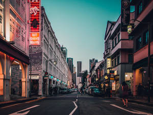 黃昏城市街道，霓虹燈招牌和殖民建築通往現代摩天大樓。