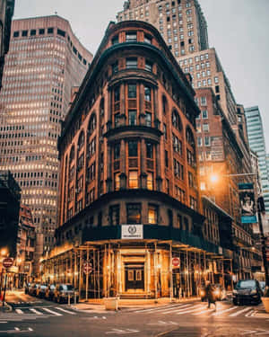 施工中的角落建築，溫暖的燈光在黃昏的城市背景下閃耀。 — 紐約市 壁紙