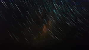 星軌弧線劃過黑暗的天空，顯露出發光的星雲。