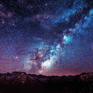 雪覆蓋的山脈在繁星點點的夜空下，銀河系清晰可見。