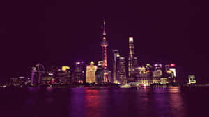 夜晚的上海天際線，燈火輝煌的摩天大樓倒映在水中。