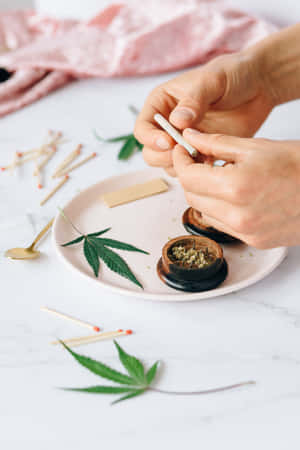 雙手在大理石表面上捲大麻煙，伴有綠葉和火柴。
