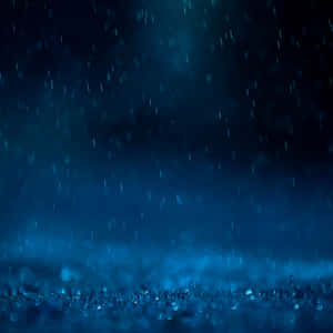 夜間在深藍色天空下，雨水落在草地上。