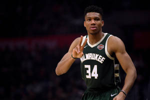 Giannis Antetokounmpo 身穿綠色密爾沃基公鹿隊球衣，在球場上做出和平手勢。