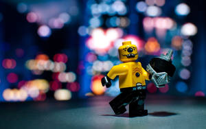 一個黃色LEGO迷你人偶，在模糊的城市夜景背景下手持武器。