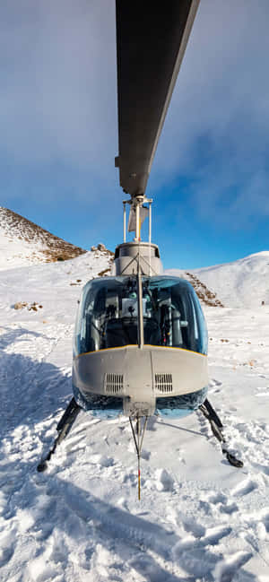 直升機停泊在白雪覆蓋的山地，藍天之下 — iPhone 16 Pro 壁紙
