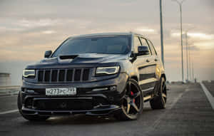 日落時分高速公路上帶紅色制動卡鉗的黑色Jeep Grand Cherokee SRT。
