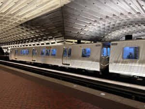 銀色地鐵列車在紅色瓷磚月台和拱形天花板的車站內。