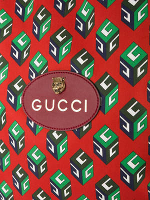 Gucci標誌貼片特寫，老虎頭在帶有重複GG立方體的紅色布料上。