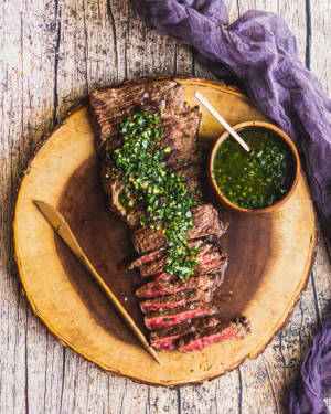 切片嘅 medium-rare 牛扒配 chimichurri 醬，放喺木盤上。 — 美食 壁紙