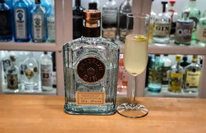 Brooklyn Gin 酒瓶和雞尾酒放在木製吧枱上，背景有酒瓶。