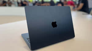 在公共空間的木桌上打開的時尚黑色 MacBook 筆記型電腦。
