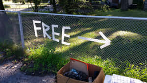 鐵絲網圍欄上畫有「FREE」指向一個裝有廢棄電子產品的紙箱。