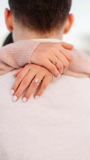 一對情侶戴著結婚戒指的手在溫柔擁抱中放在肩膀上。