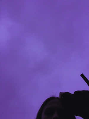 一個人仰望帶有雲朵的紫色暮色天空。