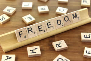 木架上拼出 freedom 的 Scrabble 字母磚，周圍散落著字母磚。