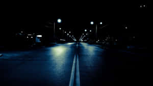 夜晚空曠的道路，路燈在濕路面上反射。