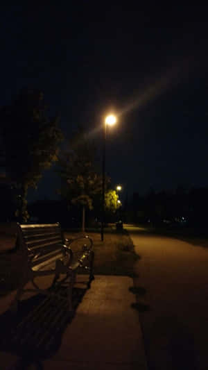 夜晚，在黑暗的公園小徑上被街燈照亮的長椅。 — 夜空 壁紙