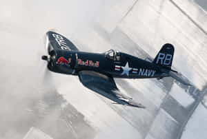 帶有 Red Bull 標誌的復古海軍戰鬥機在雪地跑道上低空飛行。
