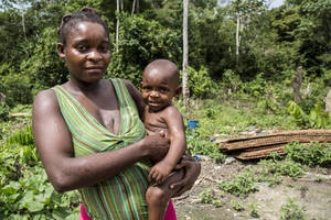 一位女性在茂密的綠色戶外環境中抱著嬰兒。