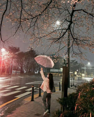 雨夜人行道上，人在櫻花下拿著粉紅雨傘。