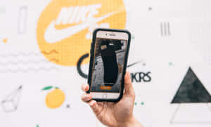 手拿著手機，在品牌牆上顯示Nike運動鞋
