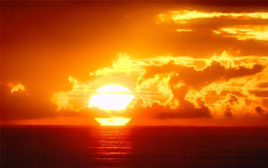 海洋上空的夕陽，天空和海水呈現熾熱的橙色和紅色